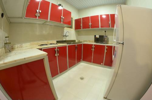uma cozinha com armários vermelhos e um frigorífico em شقق النخيل em Ar Rass