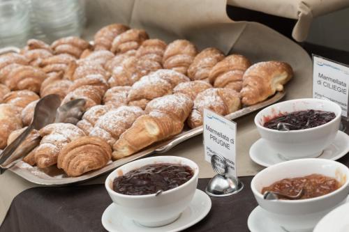 un tavolo con un vassoio di prodotti da forno e tazze di caffè di Hotel Esplanade a Cesenatico