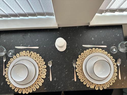 a table with two plates and forks and spoons at Lovely 2 Bedroom Apartments In Manchester Close To City Centre And Manchester City Stadium #1 in Manchester