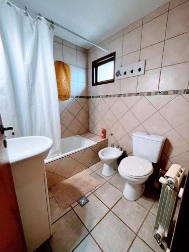 ein Badezimmer mit einem WC, einer Badewanne und einem Waschbecken in der Unterkunft Calida cabaña in Ushuaia