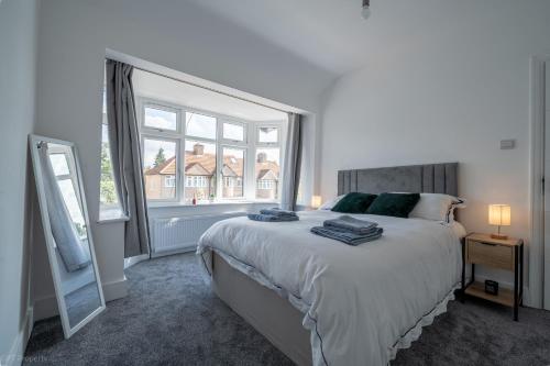 a bedroom with a large bed and a large window at Modern 5 bed home in Ealing, free driveway parking, sleeps 8 in Harrow on the Hill