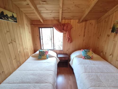 two white beds in a room with a window at Cabaña con muro de escalada in Pucón