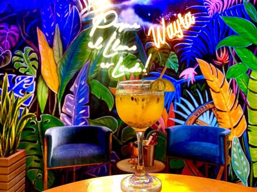 a drink sitting on a table in front of a mural at Hotel Wayra Club in Acacías