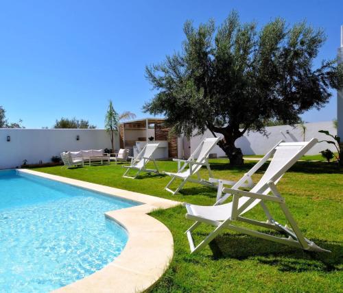 a group of lawn chairs next to a swimming pool at Dar Habiba in Hammamet