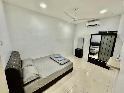 Habitación blanca con cama y espejo en Shaleishah Homestey en Kuantan