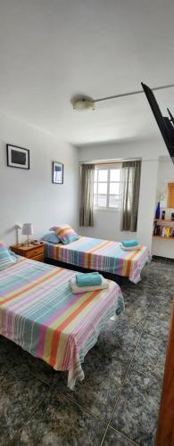 a bedroom with three beds with striped sheets at Vivienda Vacacional América in Valle Gran Rey