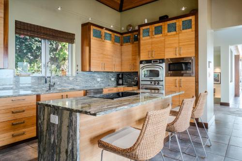 una cocina con armarios de madera y una barra con sillas en Beautiful 3 story 8,000 sq ft Oceanside Mansion en Nevis