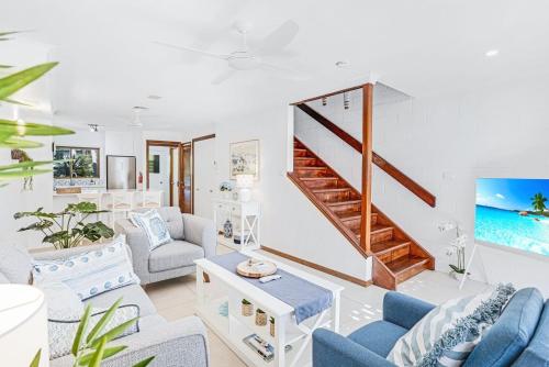 a living room with blue and white furniture and a staircase at Sandy Feet Hideaway at Four Mile Beach in Port Douglas