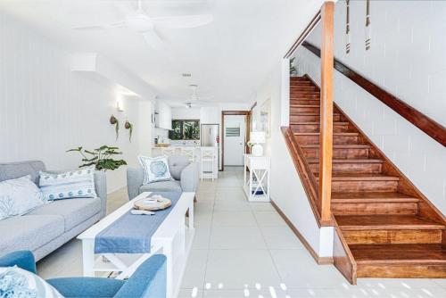 a living room with a couch and a staircase at Sandy Feet Hideaway at Four Mile Beach in Port Douglas