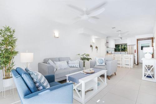 a living room with blue and white furniture at Sandy Feet Hideaway at Four Mile Beach in Port Douglas