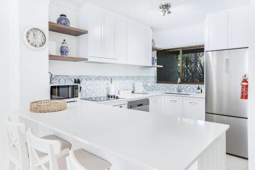a kitchen with white cabinets and a white counter top at Sandy Feet Hideaway at Four Mile Beach in Port Douglas