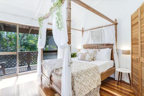 Schlafzimmer mit Himmelbett und Balkon in der Unterkunft Sandy Feet Hideaway at Four Mile Beach in Port Douglas