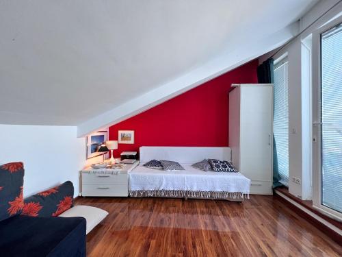 a bedroom with a bed and a red wall at Attico "NIDO" a 50m dal mare con terrazzo grande - un'oasi di pace e bellezza in Nečujam