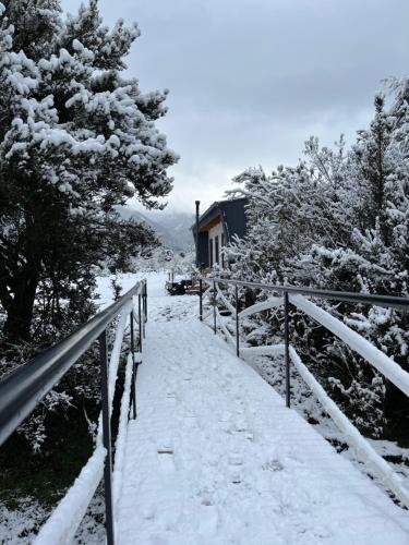 a snow covered path in front of a house at Aysén Lodge - Cabaña con Tinaja in Puerto Dunn