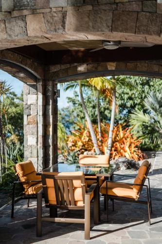 a patio with a table and chairs on a patio at Beautiful 3 story 8,000 sq ft Oceanside Mansion in Nevis