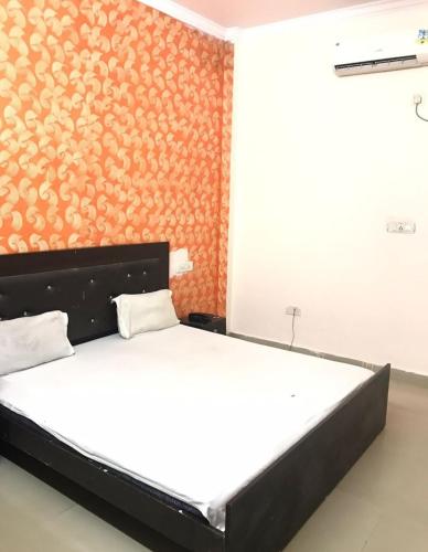 a bedroom with a bed with an orange wall at Hotel Jeet Lodge in Chandīgarh