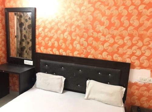 Hotel Jeet Lodge في شانديغار: غرفة نوم بسرير بحائط برتقالي