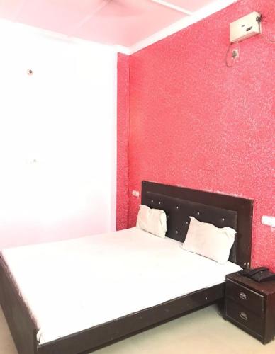 Hotel Jeet Lodge في شانديغار: غرفة نوم بسرير وجدار احمر