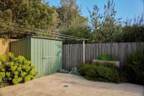 a garden with a green gate and some bushes at Marittimo in Point Lonsdale