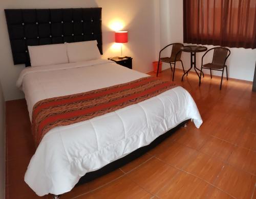 a bedroom with a large bed with a table and chairs at Cusco de mis Sueños Hostal - II in Cusco