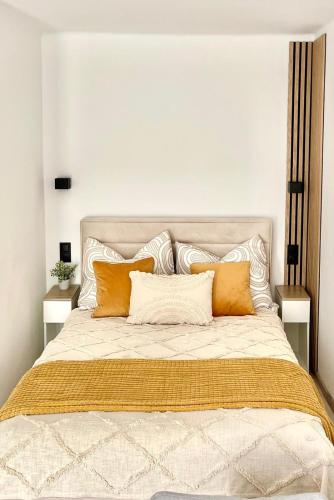 duże łóżko z pomarańczowymi i białymi poduszkami w obiekcie Studio 2 Apartment w mieście Ełk