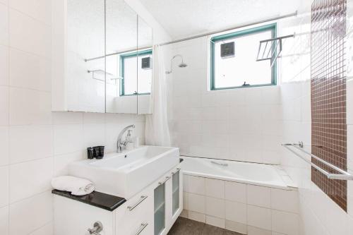 a white bathroom with a sink and a shower at Bridport Rest - A Relaxed Albert Park Abode in Melbourne