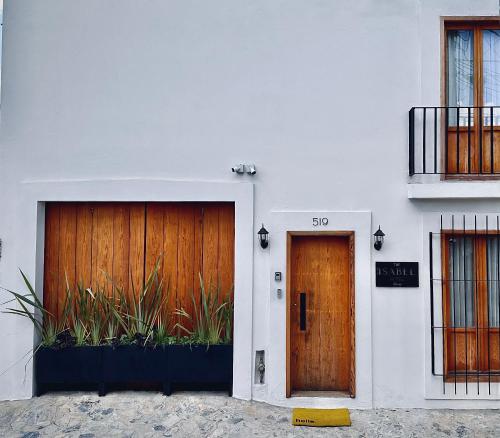 two wooden doors on a white building with plants at The Isabel Hotel in Sombrerete