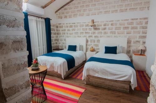a bedroom with two beds and a brick wall at Hotel de Sal Luna Salada in Colchani