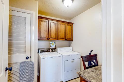 a laundry room with a washer and dryer and wooden cabinets at Cedar Park Oasis in Cedar City