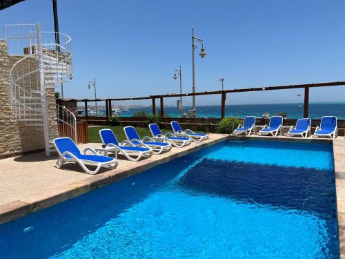 a swimming pool with chairs and the ocean in the background at Serafy City Center Hostel and Pool for Foreigners Adults Only in Hurghada