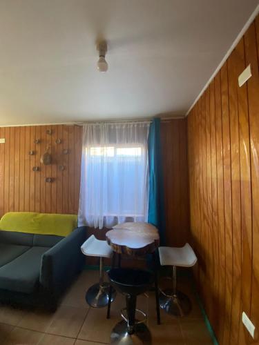 Habitación con sofá, mesa y ventana en Casa Turística Arauco, en Arauco