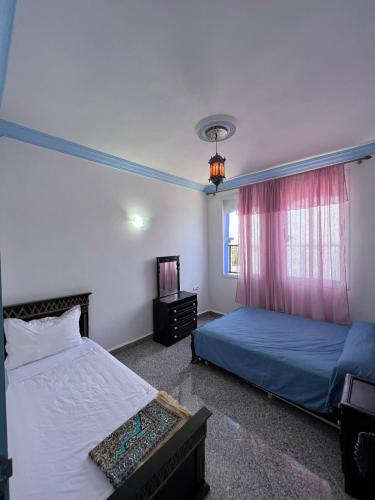 1 dormitorio con 2 camas y ventana en Casa chaara, en Chefchaouen