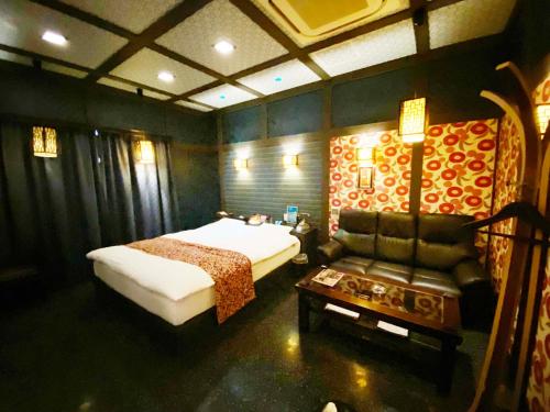a bedroom with a bed and a couch and a chair at YOL in Saijo