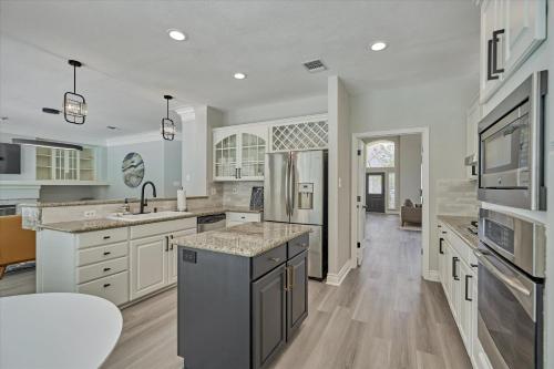 a kitchen with a sink and a refrigerator at Woodlands Contemporary 4BR3Bath with heated Pool and Spa in The Woodlands