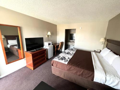 a hotel room with a bed and a flat screen tv at Red Carpet Inn Oxford in Oxford