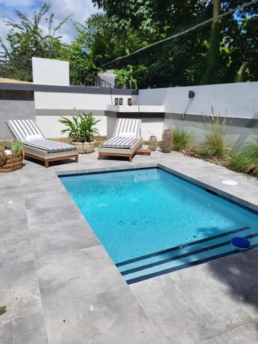 uma piscina num quintal com duas espreguiçadeiras em Le'Oasis Villa em Juncos