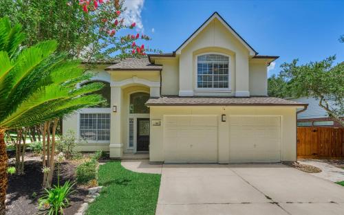 a house with a garage and a palm tree at Woodlands Contemporary 4BR3Bath with heated Pool and Spa in The Woodlands