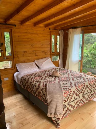a bedroom with a bed in a wooden cabin at Las Nubes Cabaña in La Mesa