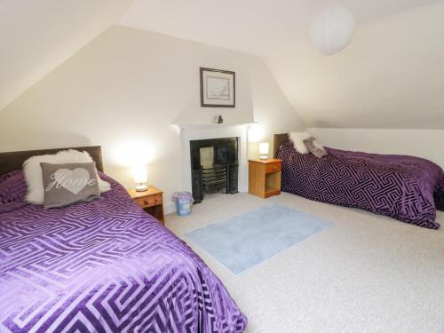 a bedroom with two beds and a fireplace at Rose Cottage in Melrose