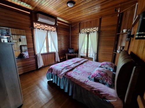 a bedroom with a bed in a wooden cabin at Palanta Roemah Kajoe Syariah Villa in Kampungdurian