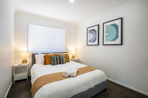 a bedroom with a bed with two lamps and a window at Alkira - Pet Friendly - 4 Mins Walk to Beach in Culburra Beach