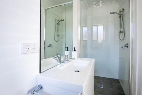 a white bathroom with a sink and a shower at Alkira - Pet Friendly - 4 Mins Walk to Beach in Culburra Beach