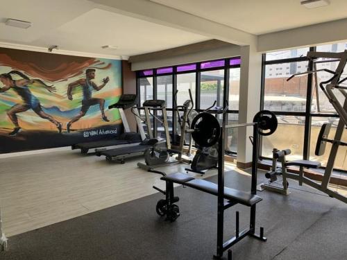 a gym with several tread machines and a mural at HOTEL CAMPO GRANDE in Campo Grande
