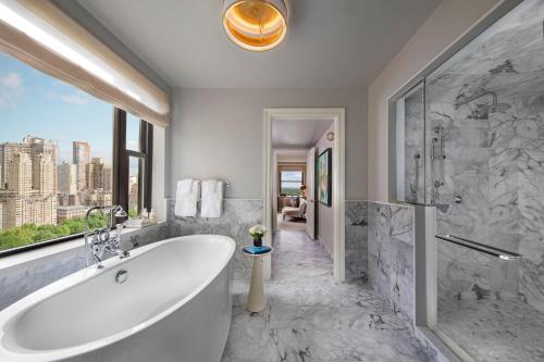 a bathroom with a tub and a shower and a window at JW Marriott Essex House New York in New York
