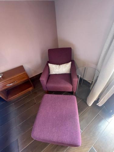a living room with a purple chair and a rug at La Estancia in San Cristóbal de Las Casas