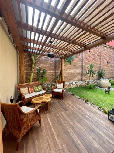 a patio with a wooden pergola with chairs and tables at La Estancia in San Cristóbal de Las Casas