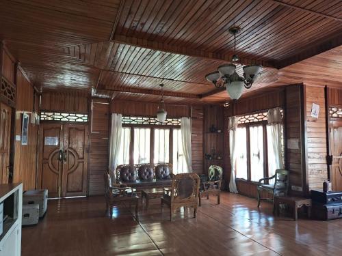 a living room with a table and chairs and wooden ceilings at Palanta Roemah Kajoe Syariah Villa in Kampungdurian