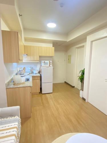 a kitchen with wooden cabinets and a white refrigerator at 17Eleven Staycation Home in Manila