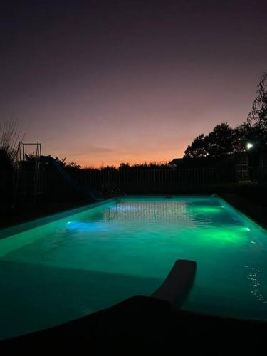 a swimming pool with green lighting at night at Linda y cómoda cabaña en un entorno natural in Los Ángeles