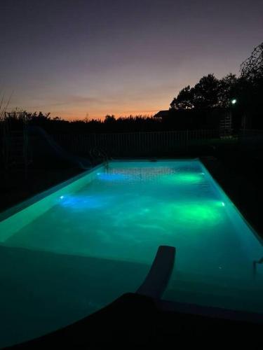 a swimming pool with green lights in a backyard at Linda y cómoda cabaña en un entorno natural in Los Ángeles